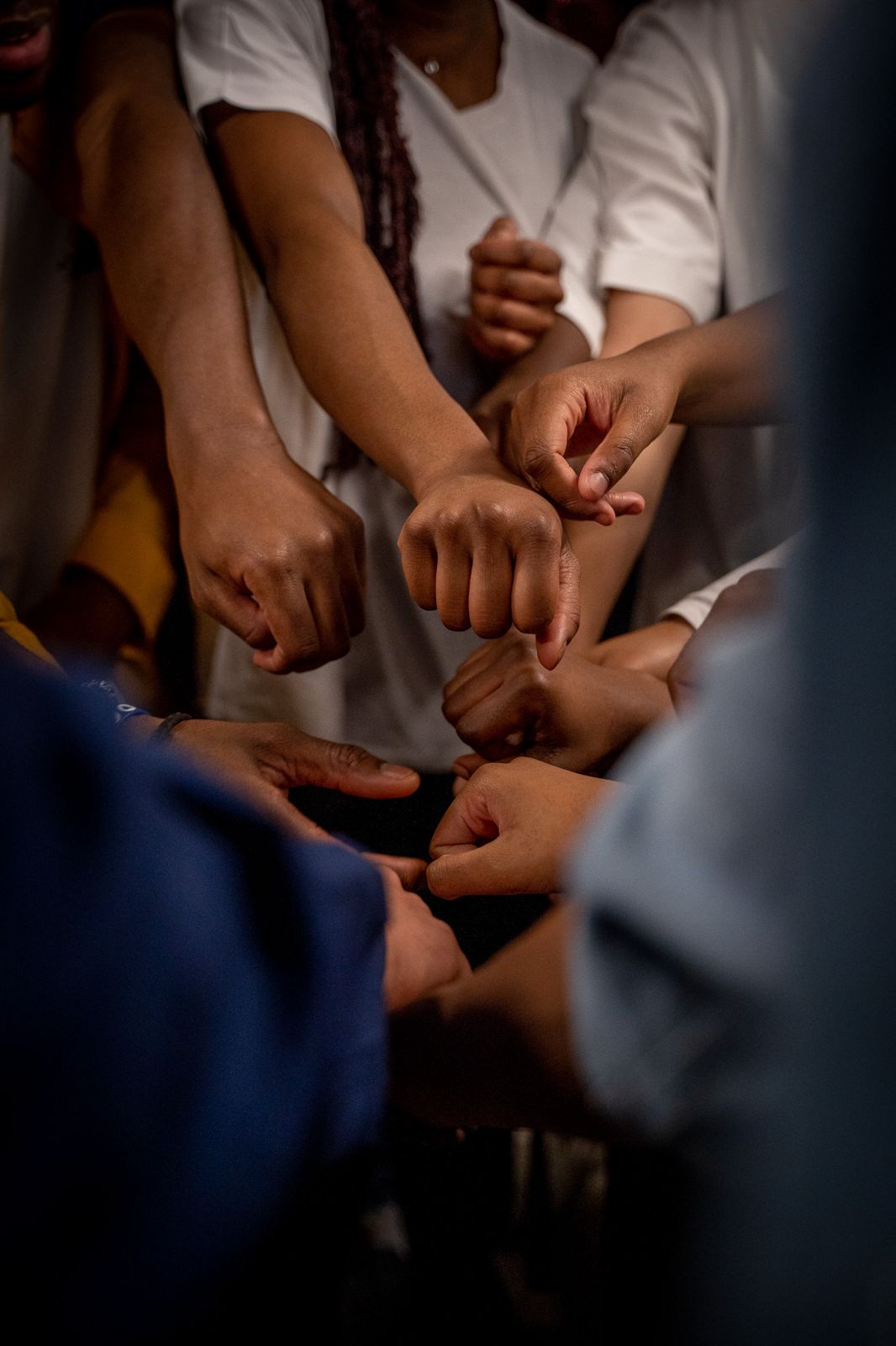Des mains d’adolescents réunies en cercle avant un temps de prière